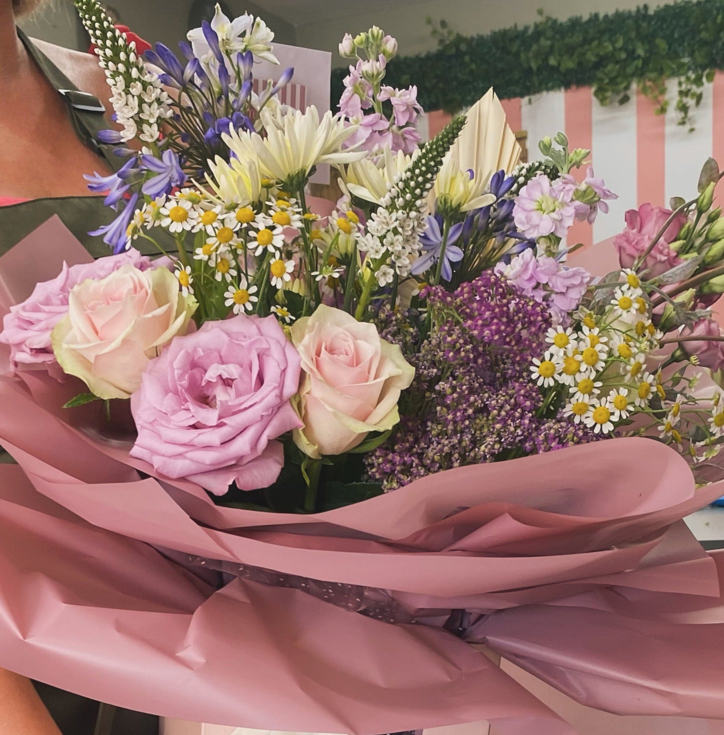 Bouquet of flowers with pink ribbon held by a person, with a blurred background