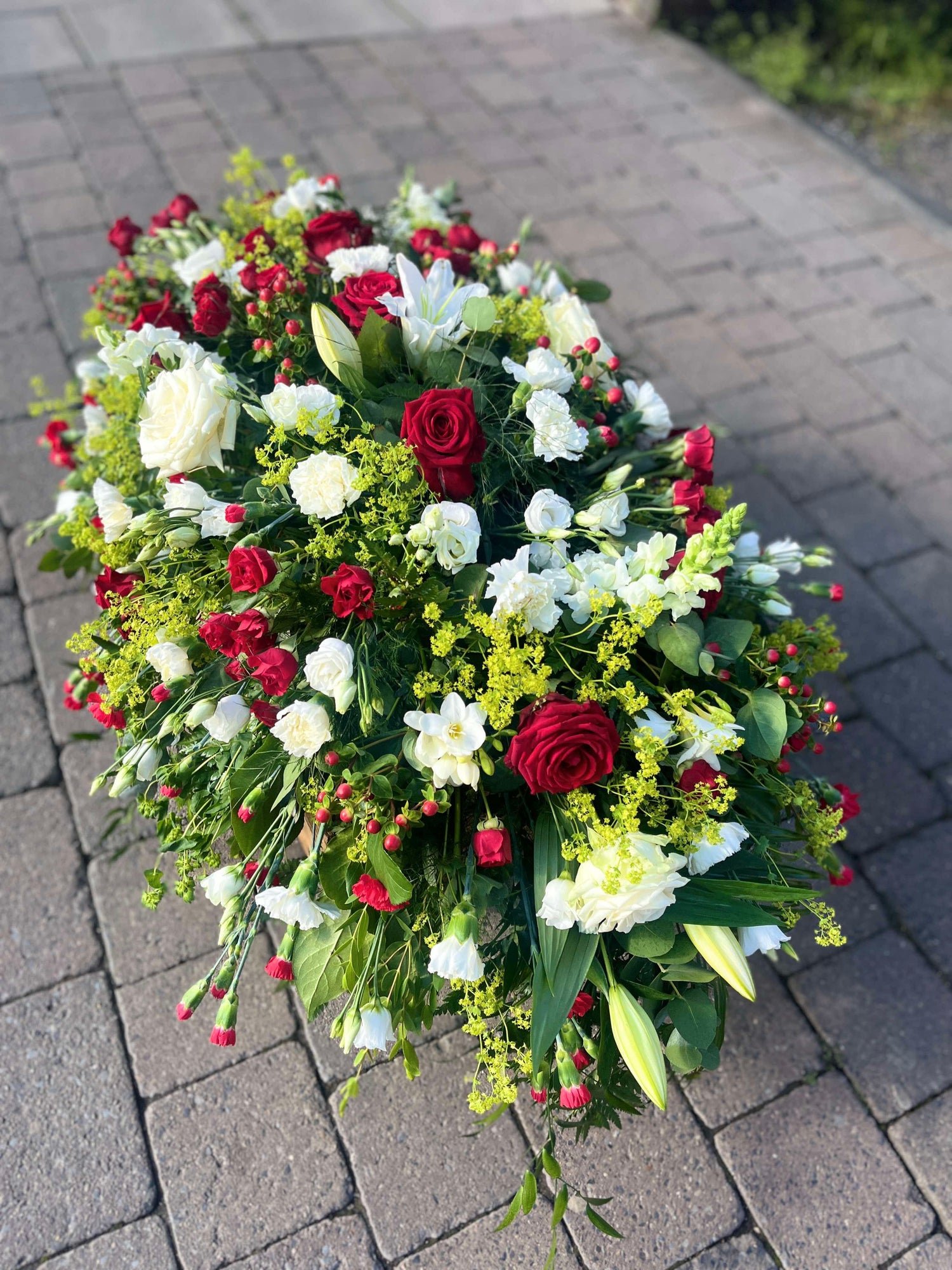 Red and white casket spray shown in 4 foot size.  Contains lillies, naomi roses, carnations and lisianthus